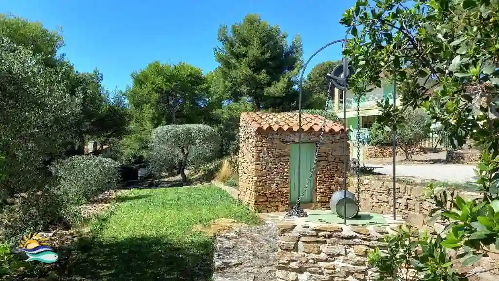 Grand jardin arboré de la villa Terre-Brûlée" avec un ancien cabanon et un puits